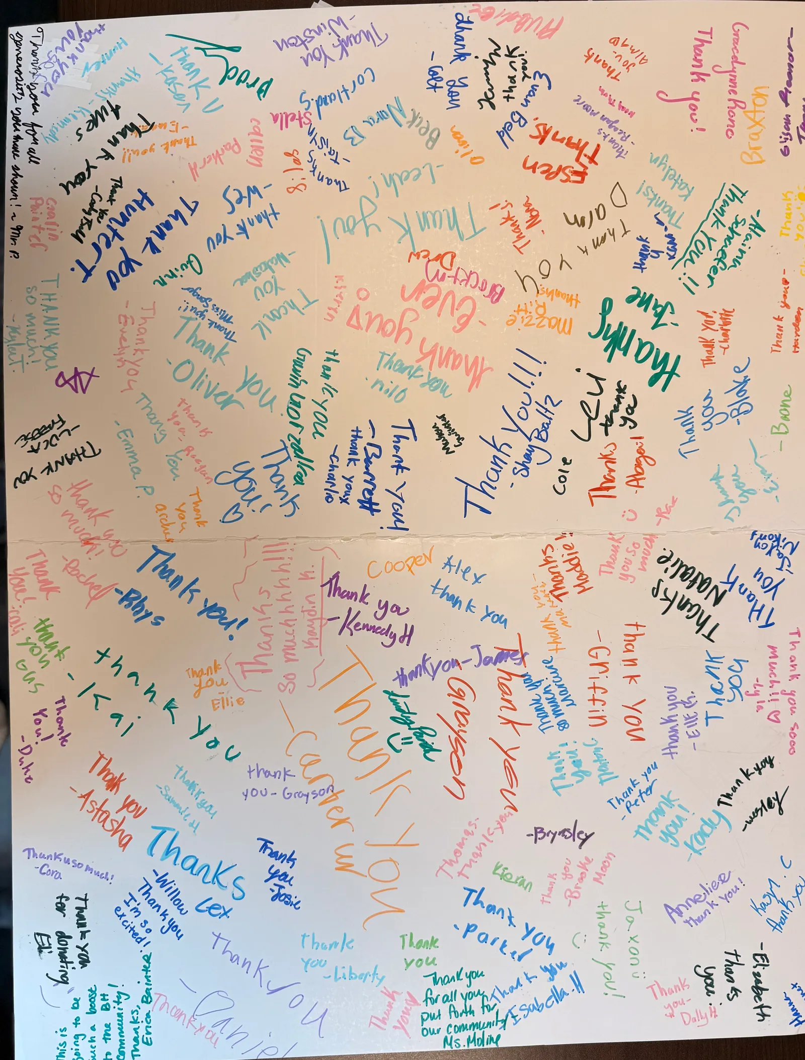 A poster filled with colorful handwritten thank-you messages and signatures.