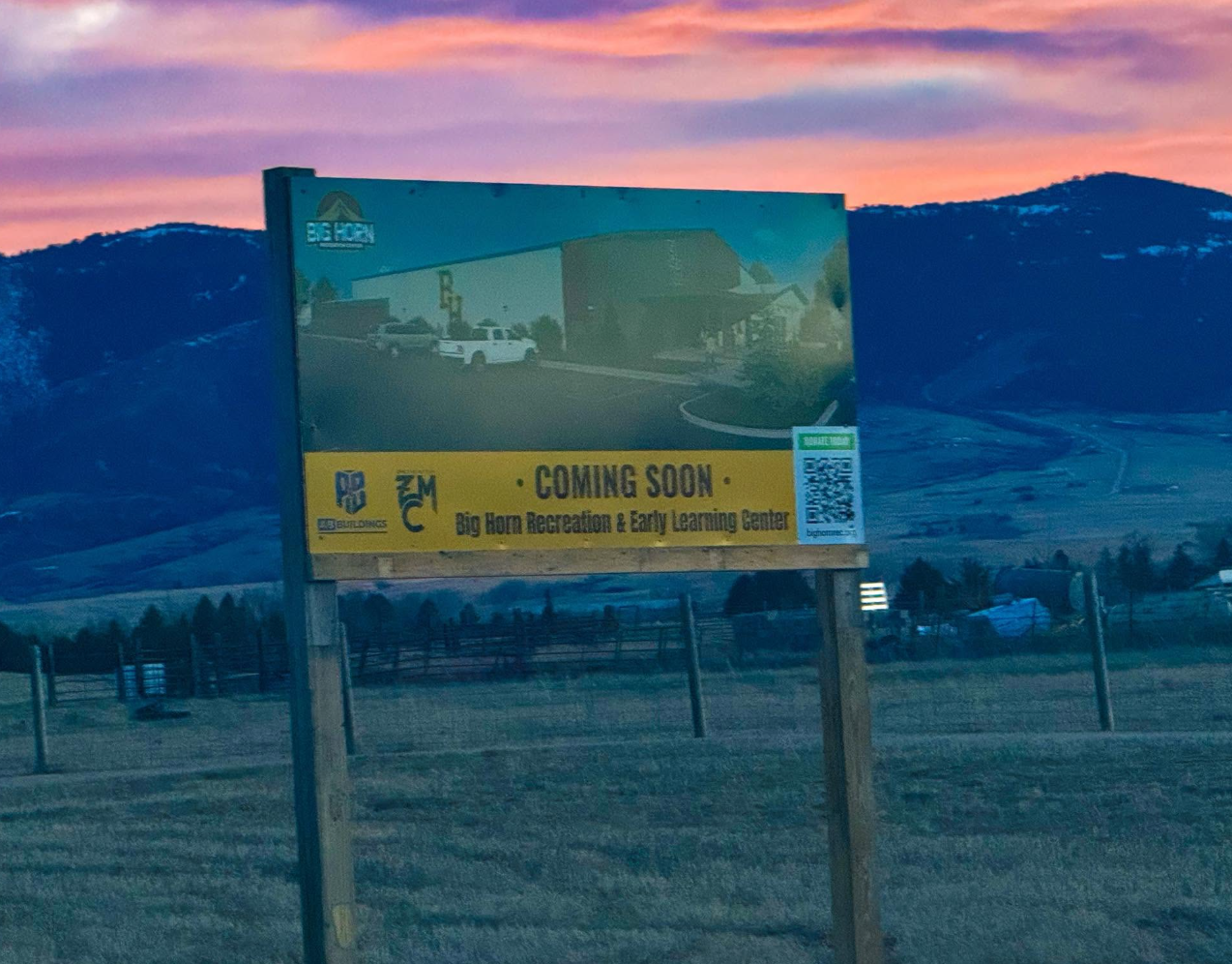 The Big Horn Recreation & Early Learning Center Coming Soon sign against the mountains at sunset.
